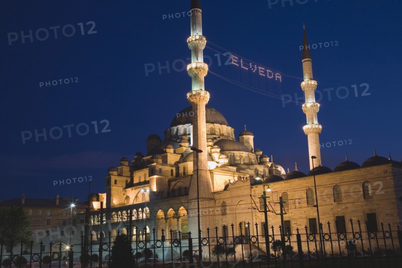 Istanbul, Turkey. Sultanahmet. The New Mosque or Yeni Camii at dusk with illuminated sign which reads Elveda meaning Go in Peace or Farewell to mark the end of Eid holiday hanging between the minarets. Seen from the Galata Bridge. Turkey Turkish Istanbul Constantinople Stamboul Stambul City Europe European Asia Asian East West Urban Destination Travel Tourism Sultanahmet New Mosque YYeni Camii Dusk Eid Elveda Sign Minaret Mionarets Muslim Mosle Islam Islamic Festival Illuminated Destination Destinations Middle East Moslem Nightfall Twilight Evenfall Crespuscle Crespuscule Gloam Gloaming Religion Religion Religious Muslims Islam Islamic Signs Display Posted Signage South Eastern Europe Turkiye Western Asia