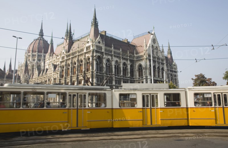 Budapest, Pest County, Hungary. Yellow tram passing the Parliament Building. Hungary Hungarian Europe European East Eastern Buda Pest Budapest City Urban Transport Tram Parliament Building Architecture Electric Color Destination Destinations Eastern Europe Parliment