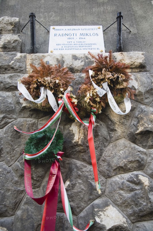 Budapest, Pest County, Hungary. Memorial to Holocaust victim Miklos Radnoti birth name Miklos Glatter 5 May 1909 to 10 November 1944 a Hungarian poet. With dried and freshly placed wreaths hung with coloured ribbon. Hungary Hungarian Europe European East Eastern Buda Pest Budapest City Memorial Stone Holocaust Miklos Radnoti Glatter Poet Wreath Flowers Ribbon Colored Cultural Cultures Destination Destinations Eastern Europe Five Order Fellowship Guild Club Ten