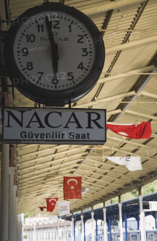 Istanbul, Turkey. Sultanahmet. Station clock giving time of three minutes to six on platform with Turkish flags hanging from roof over platform behind. Istanbul Sirkeci Terminal or Sirkeci is a terminus main station of the Turkish State Railways or TCDD in Sirkeci on the European part of Istanbul. International domestic and regional trains running westwards depart from this station which was inaugurated as the terminus of the Orient Express. Turkey Turkish Istanbul Constantinople Stamboul Stambul City Europe European Asia Asian East West Urban Destination Travel Tourism Transportt Rail Railway Train Trains Station Platform Clock Sirkeci TCCD 3 6 Destination Destinations Middle East South Eastern Europe Turkiye Western Asia