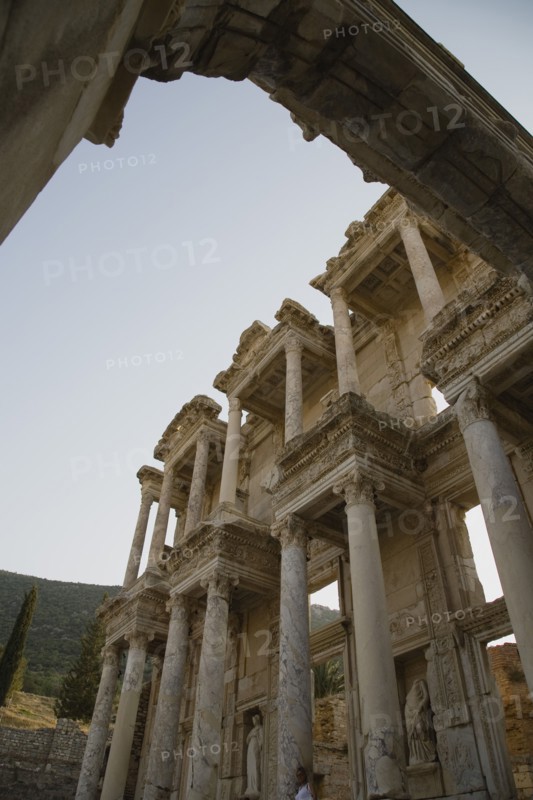 Selcuk, Izmir Province, Turkey. Ephesus. Part view of ornately carved marble facade and archway in antique city of Ephesus on the Aegean sea coast. Turkey Turkish Eurasia Eurasian Europe Asia Turkiye Izmir Province Selcuk Ephesus Ruin Ruins Roman Column Columns Facde Ancient Architecture Masonry Rock Stone Arch Destination Destinations European History Historic Middle East South Eastern Europe Water Western Asia
