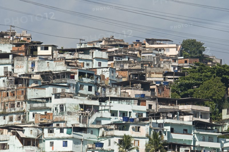 Rio de Janeiro, Brazil. Favela or slum above Centro neighbourhood with pale blue wash houses electric transmission lines and some greenery. Brasil Brazilian Brasilian South America Latin Latino American City Urban Architecture Houses Housing Homes Suade Neighborhood Neighbourhood Favela Favelas Slum Slums Church Rio de Janeiro Destination Destinations Latin America Shanty South America Southern