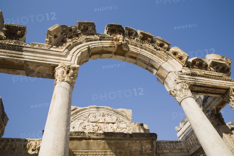 Selcuk, Izmir Province, Turkey. Ephesus. Carved archway supporting columns and wall frieze in antique city of Ephesus on the Aegean sea coast. Turkey Turkish Eurasia Eurasian Europe Asia Turkiye Izmir Province Selcuk Ephesus Ruin Ruins Roman Column Columns Facde Ancient Architecture Masonry Rock Stone Arch Blue Destination Destinations European History Historic Middle East South Eastern Europe Water Western Asia