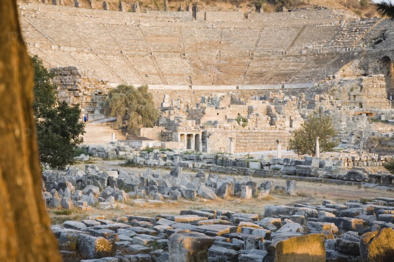Selcuk, Izmir Province, Turkey. Ephesus. Theatre and ruined buildings in antique city of Ephesus on the Aegean sea coast. Turkey Turkish Eurasia Eurasian Europe Asia Turkiye Izmir Province Selcuk Ephesus Ruin Ruins Roman Amphitheatre Aamphitheater Ancient Architecture Masonry Rock Stone Tourists Destination Destinations European History Historic Holidaymakers Middle East South Eastern Europe Tourism Water Western Asia