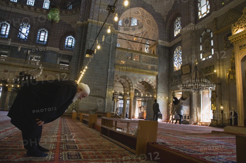 Istanbul, Turkey. Sultanahmet. The New Mosque or Yeni Camii. Tiled and highly decorated interior with elderly man worshipping prayer performing salah or prayer. Turkey Turkish Istanbul Constantinople Stamboul Stambul City Europe European Asia Asian East West Urban Destination Travel Tourism Sultanahmet New Mosque Yeni Camii Interior Muslim Moslem Islam Islamic Religion Religious Prayer Worship Man Salah Worshipping Destination Destinations Male Men Guy Middle East Old Senior Aged One individual Solo Lone Solitary Performance Religion Religious Muslims Islam Islamic South Eastern Europe Turkiye Western Asia