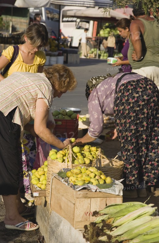 Kusadasi, Aydin Province, Turkey. Woman from local farm selling fruit and vegetables to shoppers at fresh produce market in town. Turkey Turkish Eurasia Eurasian Europe Asia Turkiye Aydin Province Kusadasi Market Markets Food Fryut Veg Vegetable Vegetables Produce Women Female Woman Selling Vendor Buying Fig Figs Corn Cob Cobs Destination Destinations European Female Woman Girl Lady Female Women Girl Lady Middle East South Eastern Europe Western Asia