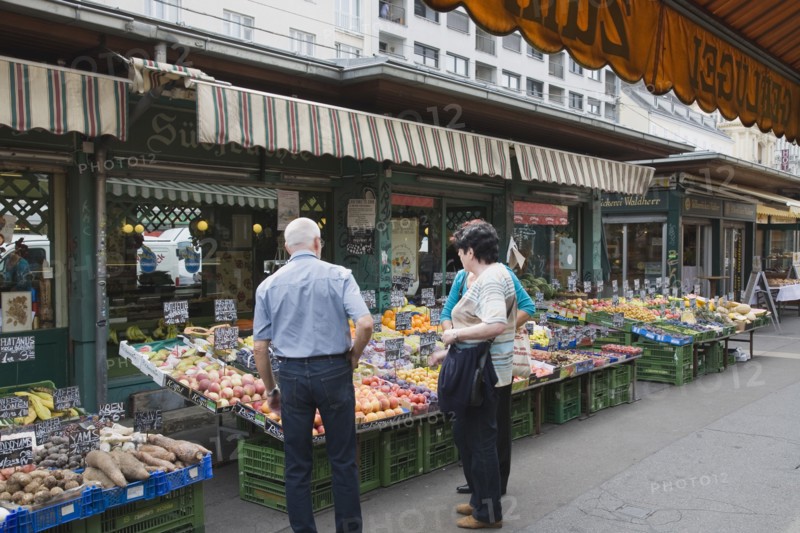 Vienna, Austria. The Naschmarkt. Customers at fresh produce stall looking at display that includes peaches plums pears and oranges. Austria Austrian Republic Vienna Viennese Wien Europe European City Capital Naschmarkt Market Display Fresh Food Fruit Vegetables Veg Vegetable Stall Shop Store Destination Destinations Osterreich Viena Western Europe