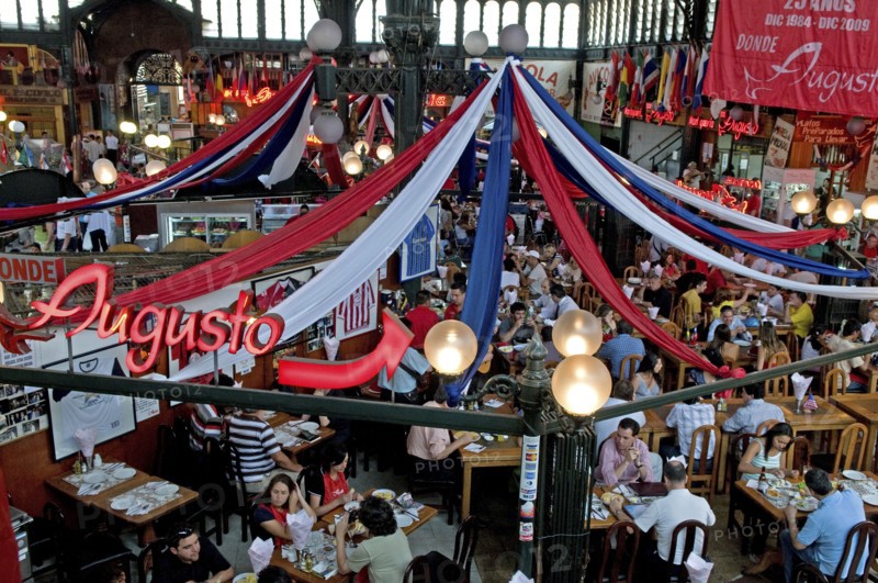 Santiago, Chile. Seafood restaurant section of Central Market with diners at tables eating under red white and blue hanging decorations. Chile Chilean South America American Hispanic Santiago City Cityscape Urban Travel Destination Vacation Holiday Mercado Central Market Retaurant Cafe Seafood Fish View Over Diners People Crowded Tables Eating Food Drink Bunting Streamers Bar Bistro Destination Destinations Latin America Latino South America Southern