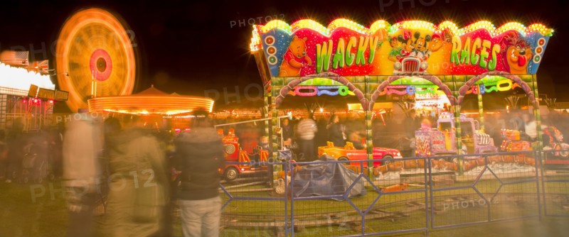 Lancing, West Sussex, England. Entertainment Funfairs Rides illuminated at night. England English UK United Kingdom GB Great Britain British Europe European West Sussex Lancing Funfair Rides Night Entertainment Leisure Color Colour Colorful Colourful Colored Coloured People Crowd Blur Blurred Ferris Wheel Big Neon Light