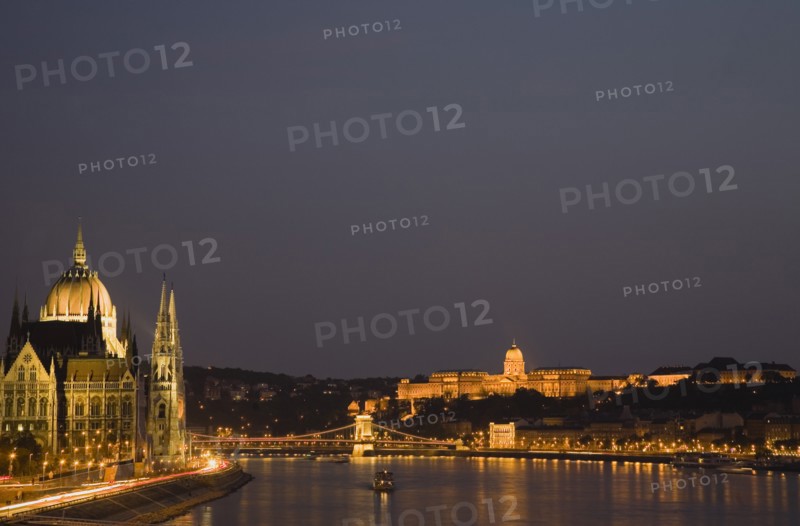 Budapest, Hungary. View along the River Danube at night with the Parliament building on the left the Chain Bridge and the Royal Palace on the right all illuminated brightly. Hungary Hungarian Europe European East Eastern City Cityscape Skyline Night Nighttime Dark Lights Lit Illuminated River Danube Parliament Royal Palace Chain Bridge Travel Destination Holiday Vacation Break Buda Pest Budapest Citiscape Building Buildings Urban Architecture Destination Destinations Eastern Europe Nite Parliment