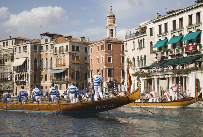 Venice, Veneto, Italy. Participants in the Regata Storico historical Regatta held annually in September wearing traditional costume and approaching the Rialto bridge with onlookers gathered on the balconies of canalside buildings behind. Teams represent Sestiere districts of Venice in traditional races. Italy Italia Italian Venice Veneto Venezia Europe European City Regata Regatta Gondola Gondola Gondolas Gondolier Boat Architecture Exterior Classic Classical Destination Destinations History Historic Holidaymakers Older Southern Europe Tourism Tourist