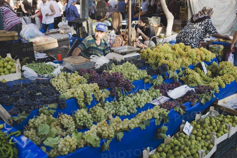 Kusadasi, Aydin Province, Turkey. Stall with display of grapes figs beans and chilies for sale in busy market. Asian Color Destination Destinations European Middle East South Eastern Europe Turkish Turkiye Western Asia