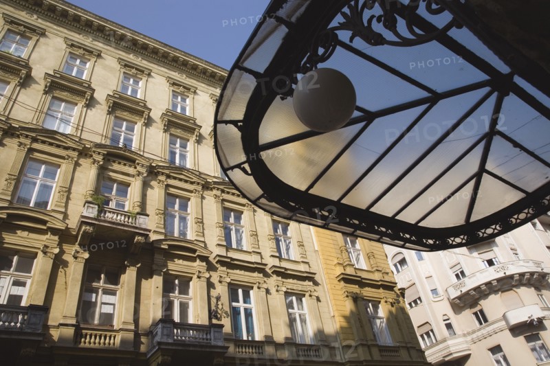 Budapest, Pest County, Hungary. Art Nouveau era apartment exterior facades with part seen underside of decorative metal and glass roof in foreground. Hungary Hungarian Europe European East Eastern Buda Pest Budapest City Architecture Apartment Apartments Buildings Buildings Exterior Facade Art Nouveau Destination Destinations Eastern Europe Flat