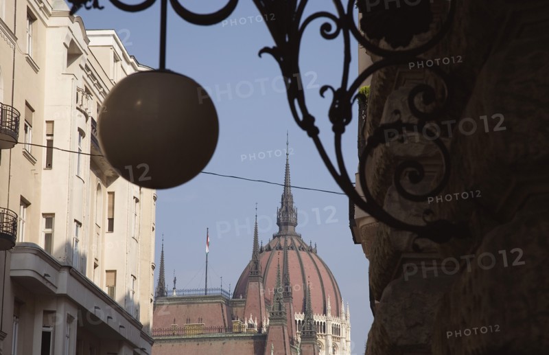 Budapest, Pest County, Hungary. Art Nouveau era apartment facades with domed roof of Hungarian Parliament Building behind and decorative metalwork and hanging spherical light in foreground. Hungary Hungarian Europe European East Eastern Buda Pest Budapest City Architecture Apartment Apartments Exteriors Exterior Facade Facades Nouveau Art Lamp Light Blue Destination Destinations Eastern Europe Flat Parliment
