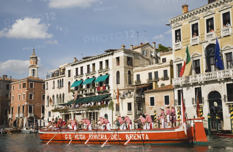 Venice, Veneto, Italy. Participants in the Regata Storico historical Regatta held annually in September wearing traditional costume approaching the Rialto bridge with onlookers gathered on the balconies of canalside buildings behind. Teams represent Sestiere districts of Venice in traditional races. Italy Italia Italian Venice Veneto Venezia Europe European City Regata Regatta Gondola Gondola Gondolas Gondolier Boat Architecture Exterior Water Classic Classical Destination Destinations History Historic Holidaymakers Older Southern Europe Tourism Tourist