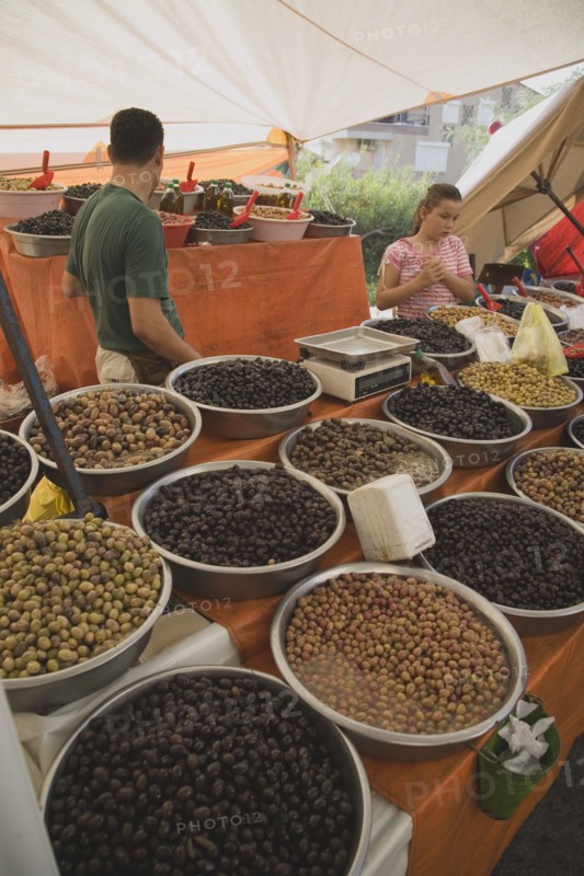 Kusadasi, Aydin Province, Turkey. Stall at weekly market selling olives and nuts with male stallholderand young girl standing behind display and set of electronic scales. Turkey Turkish Eurasia Eurasian Europe Asia Turkiye Aydin Province Kusadasi Market Markets Stall Display Olive Olives Dried Nut Nuts Scales Electronic Multi Muliple Color Colour Colors Colours Colored Coloured Destination Destinations European Immature Kids Middle East South Eastern Europe Western Asia