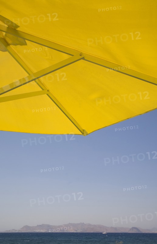 Kos, Dodecanese Islands, Greece. Underside of bright yellow sun umbrella framing view across sea to distant coastline. Greece Greek Europe European Vacation Holiday Holidays Travel Destination Tourism Ellas Hellenic Docecanese Kos Beach Sea Umbrella Parasol Yellow Blue Color Destination Destinations Ellada Sand Sandy Beaches Tourism Seaside Shore Tourist Tourists Vacation Southern Europe Water