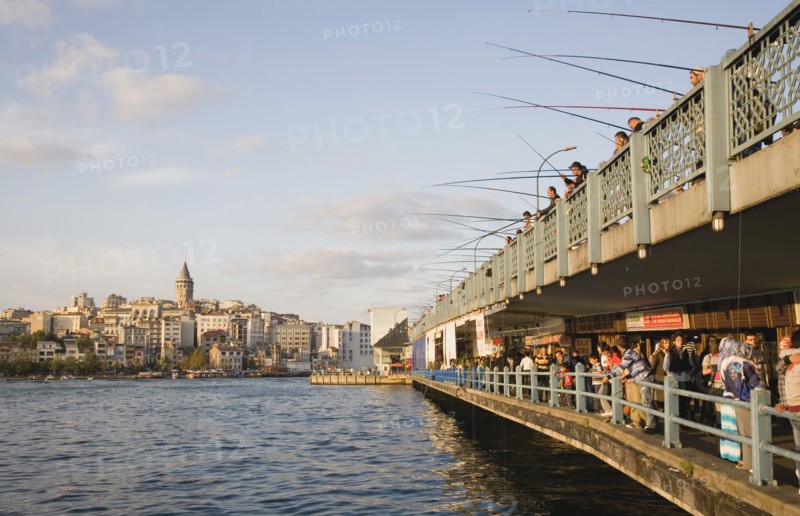 Istanbul, Turkey. Sultanahmet. View towards Galata Tower with men fishing from Galata bridge above fish restaurants below. Turkey Turkish Istanbul Constantinople Stamboul Stambul City Europe European Asia Asian East West Urban Destination Travel Tourism Sultanahmet Bosphorous Galata Bridge People Crowd Fishing Rods Men Destination Destinations Male Man Guy Middle East South Eastern Europe Turkiye Western Asia