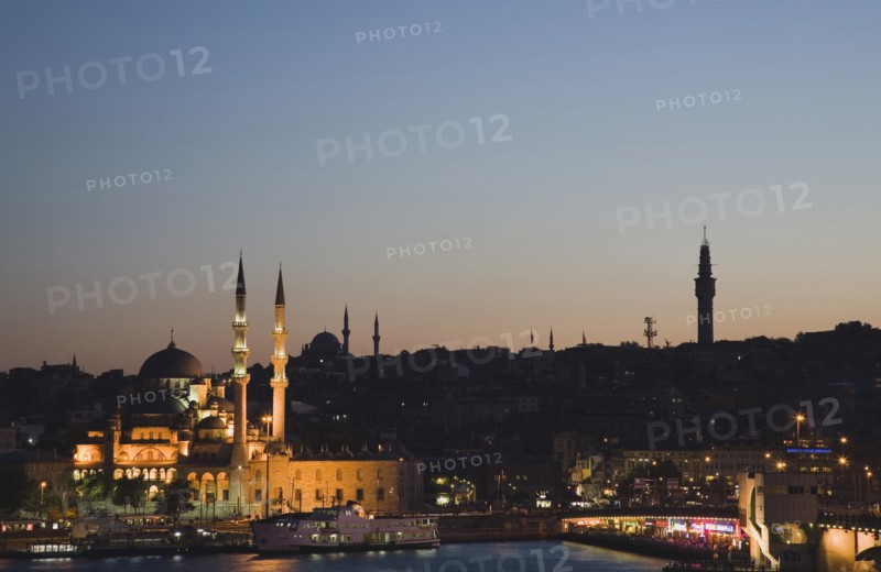 Istanbul, Turkey. Sultanahmet. The Golden Horn. The New Mosque or Yeni Camii at left the Galata Bridge and Suleymaniye Mosque at right. Buildings illuminated at dusk. Turkey Turkish Istanbul Constantinople Stamboul Stambul City Europe European Asia Asian East West Urban Skyline Destination Travel Tourism Sultanahmet Golden Horn New Mosque Yeni Camii Galata Bridge Suleymaniye Dusk Sunset Night Illuminated Skyline Minarets Water Citiscape Building Buildings Urban Architecture Destination Destinations Middle East Nightfall Twilight Evenfall Crespuscle Crespuscule Gloam Gloaming Nite South Eastern Europe Sundown Atmospheric Turkiye Western Asia