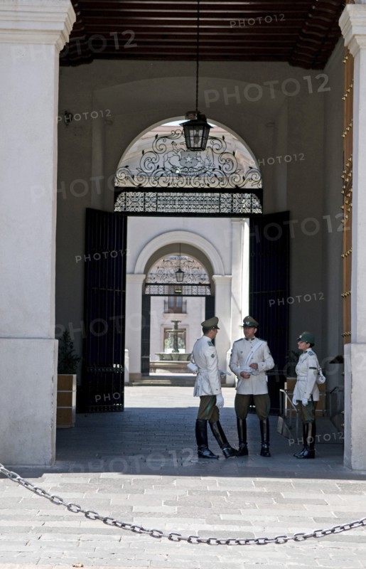 Santiago, Chile. Main entrance of the Palacio de la Moneda Presidential Palace guarded by high booted carabineros police a chain prevents tourists and onlookers from getting too close. Chile Chilean South America American Hispanic Santiago City Cityscape Urban Palacio de la Moneda Presidential Palace Guards Guard Guarded Security Poilce Policemen Policewoman Uniformed Carabineros Entrance Destination Destinations Holidaymakers Latin America Latino South America Southern Tourism