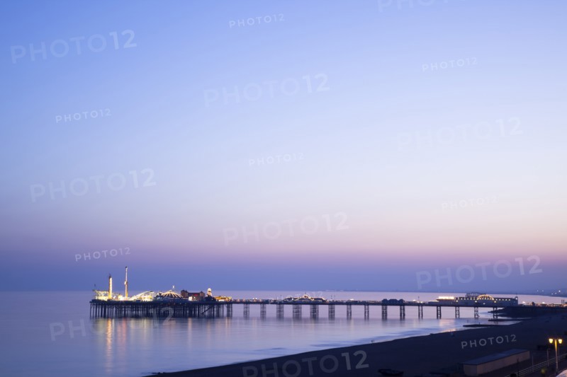 Brighton, East Sussex, England. View of the pier at sunset from the seafront promenade in Kemptown. England English UK United Kingdom United Kingdom GB Great Great Britain Britain British Europe European East Sussex East Sussex County Brighton Kemptown Marine Parade Sea Seafront Promenade Pier Sunet Blue Sky Illuminated Lit up Travel Silhouette Silhouetted