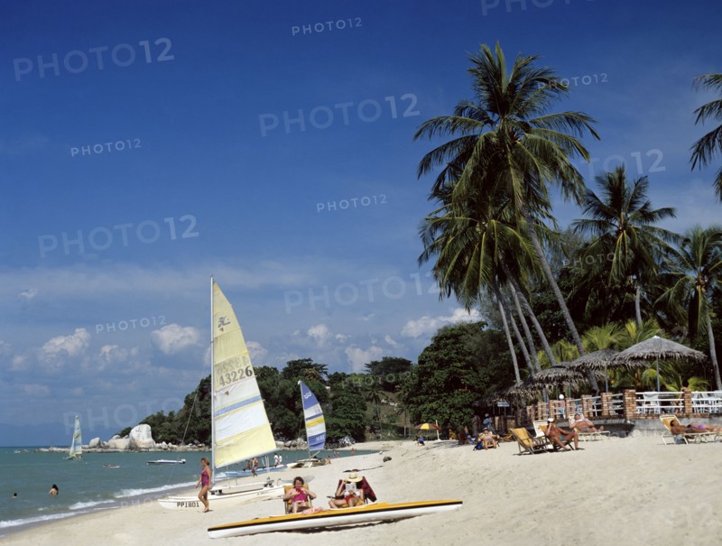 Batu Ferringhi, Penang, Malaysia. Beach scene with tourists sunbathing. Malaysia Malaysian Palmenstrand Penang Batu Ferringhi Beach Palm Tree Sand Shore Coast Sea Water Sail Boat Relax Hoby Cat Catamaran Tourist Tourist Sunbathing Beach Holiday Vacation Travel Asian Blue Destination Destinations Holidaymakers Sand Sandy Beaches Tourism Seaside Shore Tourist Tourists Vacation Sightseeing Southeast Asia Southern Sunbather Water