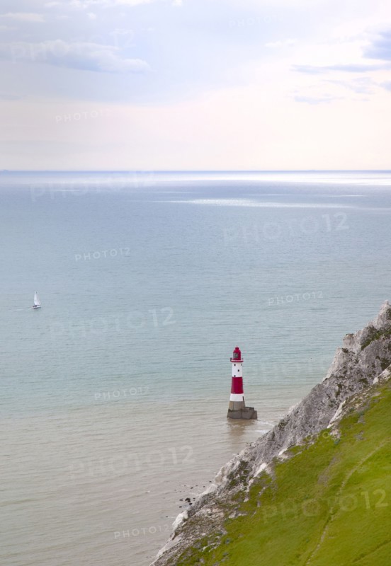 Eastbourne, East Sussex, England. Beachy Head view of the lighthouse at the base of the chalk cliffs. England English UK United Kingdom GB Great Britain Birtish East Sussex County Eastbourne Beachy Head Sea Coast Chalk Cliff Cliffs White Lighthouse Light House Boat Ship Transport Warning