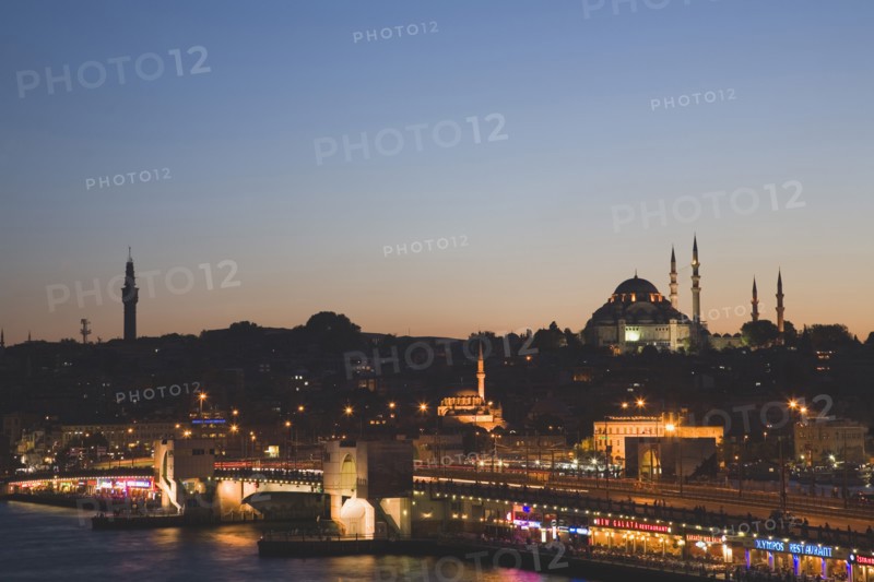 Istanbul, Turkey. Sultanahmet. The Golden Horn. The New Mosque or Yeni Camii at left the Galata Bridge and Suleymaniye Mosque at right illuminated at dusk. Turkey Turkish Istanbul Constantinople Stamboul Stambul City Europe European Asia Asian East West Urban Skyline Destination Travel Tourism Sultanahmet Golden Horn New Mosque Yeni Camii Galata Bridge Suleymaniye Dusk Sunset Night Illuminated Skyline Minarets Water Citiscape Building Buildings Urban Architecture Destination Destinations Middle East Nightfall Twilight Evenfall Crespuscle Crespuscule Gloam Gloaming Nite South Eastern Europe Sundown Atmospheric Turkiye Western Asia