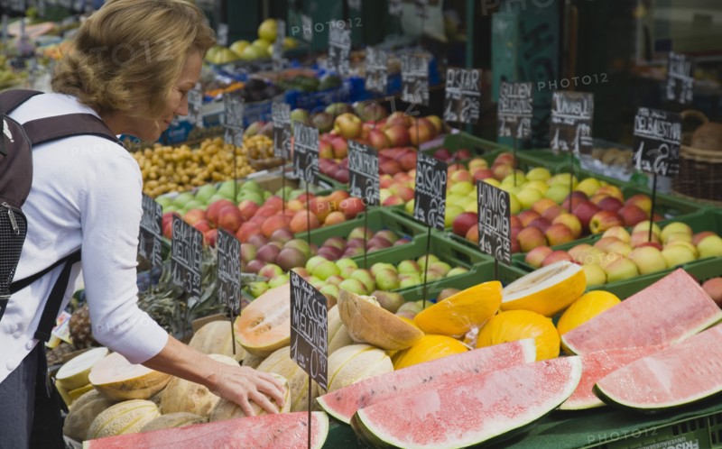 Vienna, Austria. The Naschmarkt. Female customer selecting melon from display on market fruit stall that also includes apples and pineapple. Austria Austrian Republic Vienna Viennese Wien Europe European City Capital Naschmarkt Market Display Fresh Food Fruit Stall Shop Store Destination Destinations One individual Solo Lone Solitary Osterreich Viena Western Europe