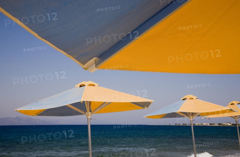 Kos, Dodecanese Islands, Greece. Blue and yellow striped parasols on beach outside Kos Town. Greece Greek Europe European Vacation Holiday Holidays Travel Destination Tourism Ellas Hellenic Docecanese Kos Sea Umbrella Umbrellas Parasol Parasols Blue Orange Color Destination Destinations Ellada Sand Sandy Beaches Tourism Seaside Shore Tourist Tourists Vacation Southern Europe Water