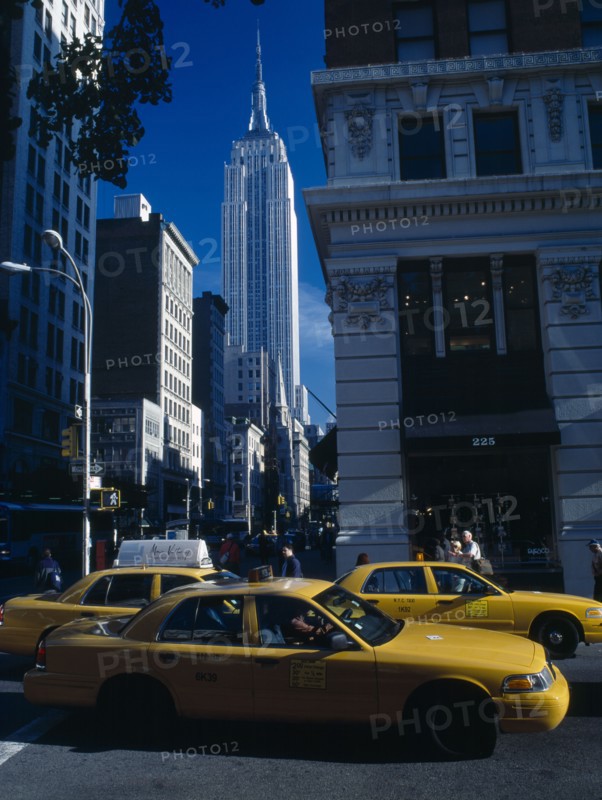 New York City, New York, USA. View along 5th Avenue toward the Empire State Building with yellow taxis in the foreground Cab American North America Northern United States of America