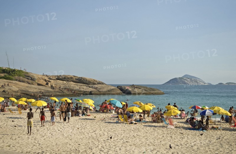 Rio de Janeiro, Brazil. Arpoador end of Ipanema beach with yellow umbrellas blue sea and sky swimmers in sea and on rocks and pigeons on beach. Brazil Brasil Brazilian Brasilian South America Latin Latino American City Travel Destination Urban Vacation Beach Beaches People Sunbathing Crowds Umbrellas Parasols Swimmers Swimming Arpoador Ipanema Destination Destinations Holidaymakers Latin America Sand Sandy Beach Tourism Seaside Shore Tourist Tourists Vacation Sand Sandy Beaches Tourism Seaside Shore Tourist Tourists Vacation South America Southern Sunbather Water