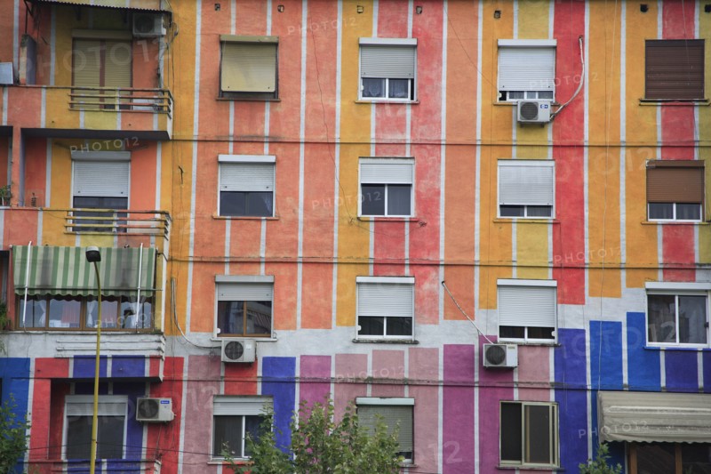 Albania, Tirane, Tirana, Detail of exterior facade of apartment block painted in stripes of different colours with multiple windows and balconies.
