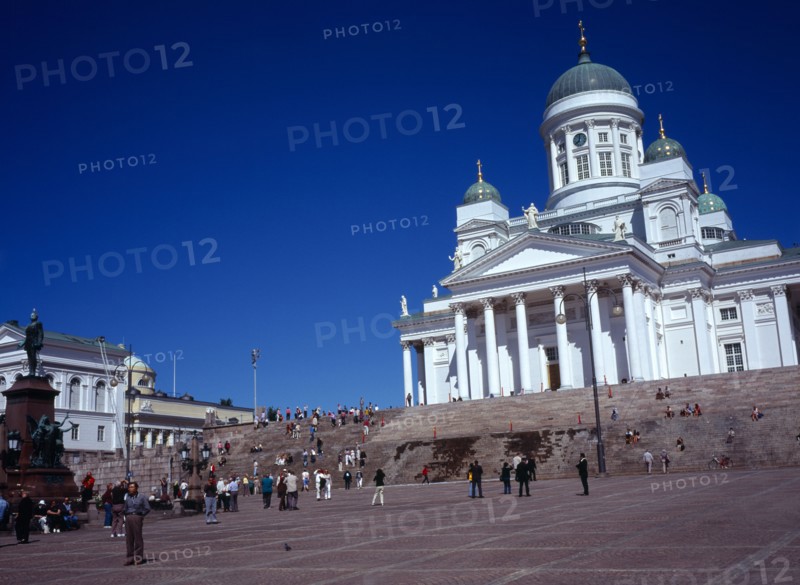 Finland, Helsinki, Senate Square and Lutheran Cathedral.  White exterior facade in neo-classical style with green domed roof and statues  at top of flight of steps with crowds of visitors.