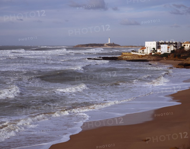Spain, Andalucia, Cadiz, Cape Trafalgar and Los Canos de Meca village apartments overlooking beach with surf breaking on the sand.