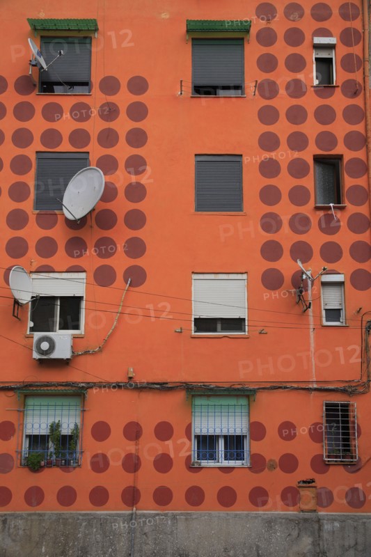 Albania, Tirane, Tirana, Detail of exterior facade of apartment block painted orange with pattern of red circles  multiple windows and satelite dishes.