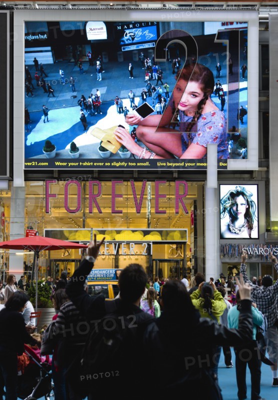 USA, New York, New York City, Manhattan  People waving and looking at themselves in a giant live real time TV video LED screen in Times Square above Forever 21 clothing shop.