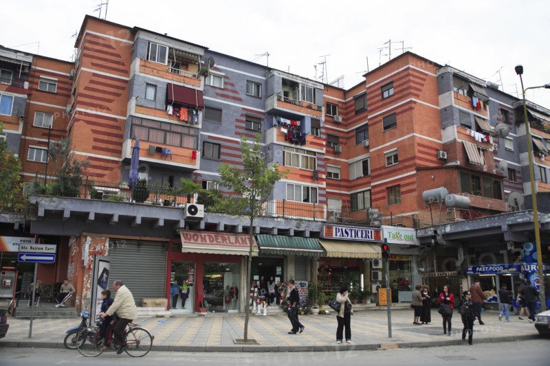 Albania, Tirane, Tirana, Colourful apartment buildings with washing hanging from balconies and shops and busy street below.