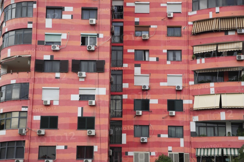 Albania, Tirane, Tirana, Part view of exterior facade of colourful apartment building with shuttered windows and air conditioning units.