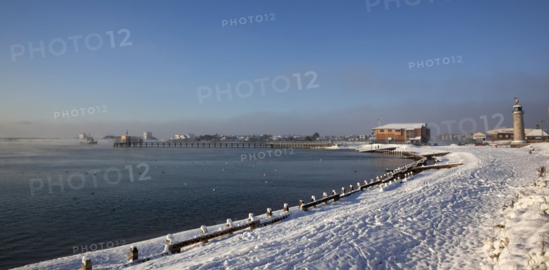 England, West Sussex, Shoreham-by-Sea , Mist rising from harbour waters on frosty morning with snow on the beach.