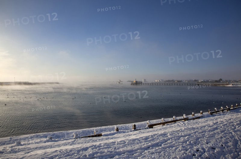 England, West Sussex, Shoreham-by-Sea , Mist rising from harbour waters on frosty morning with snow on the beach.