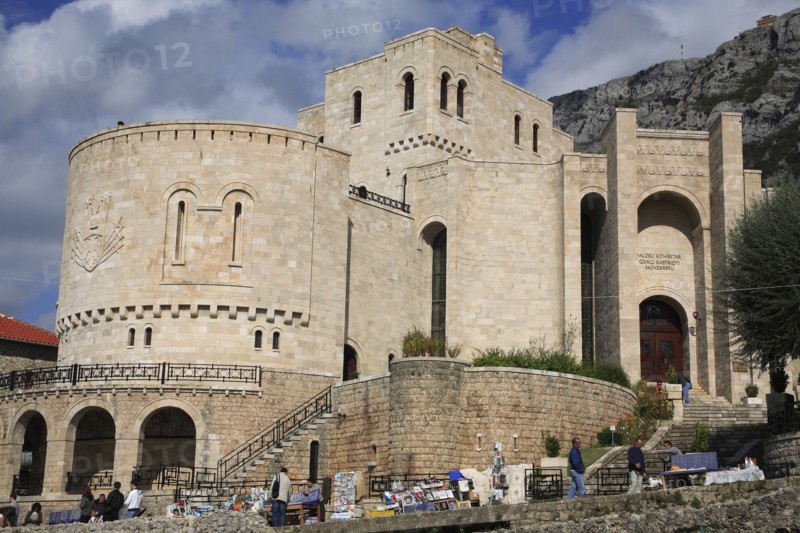 Albania, Kruja, Kruja Castle and Skanderbeg Museum exterior with tourist visitors and souvenir stalls in foreground.