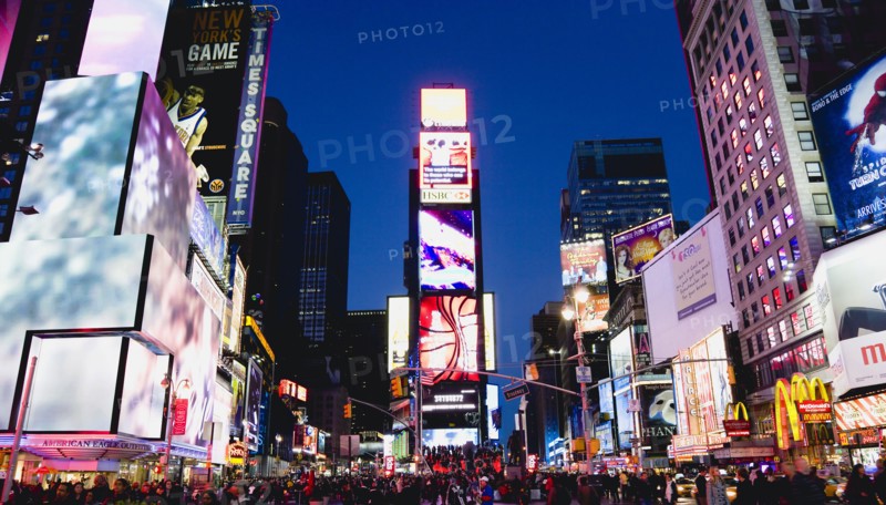 USA, New York, New York City, Manhattan  People walking at night in Times Square at the junction of 7th Avenue and Broadway below buildings with advertising on large video screens.