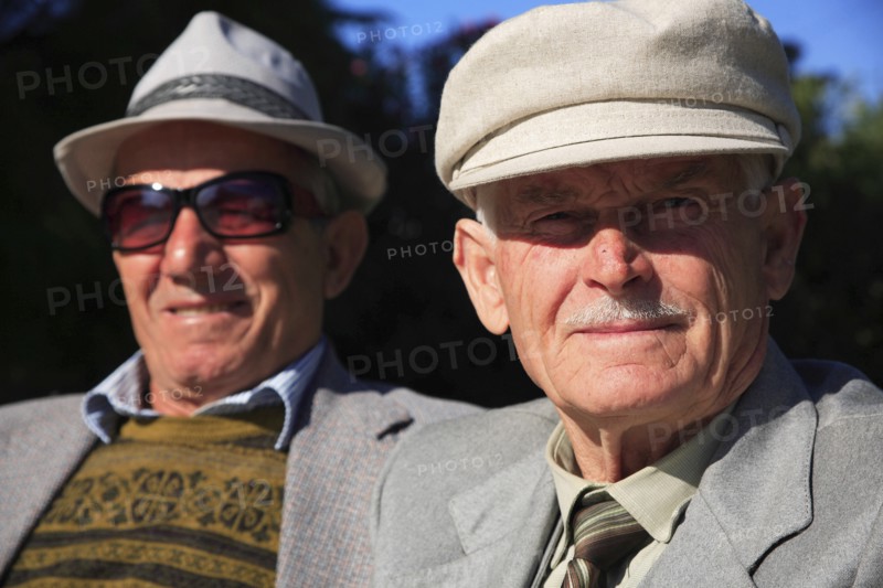 Albania, Tirane, Tirana, Head and shoulders portrait of two men. One elderly looking straight to camera  one wearing sun-glasses slightly behind  both wearing hats.