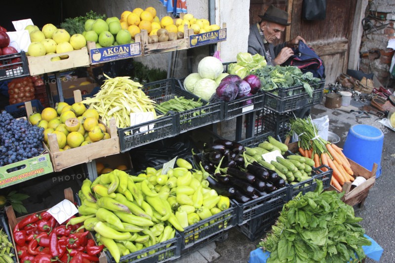 Albania, Tirane, Tirana, Display of fruit and vegetables including peppers  cabbage and grapes at grocers shop in the Avni Rustemi market. Shoe mender in doorway at side.