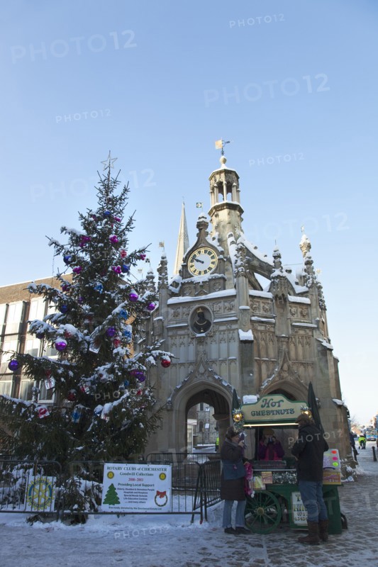 England, West Sussex, Chichester, The Cross and Christmas tree in snow with roast chestnut vendor.