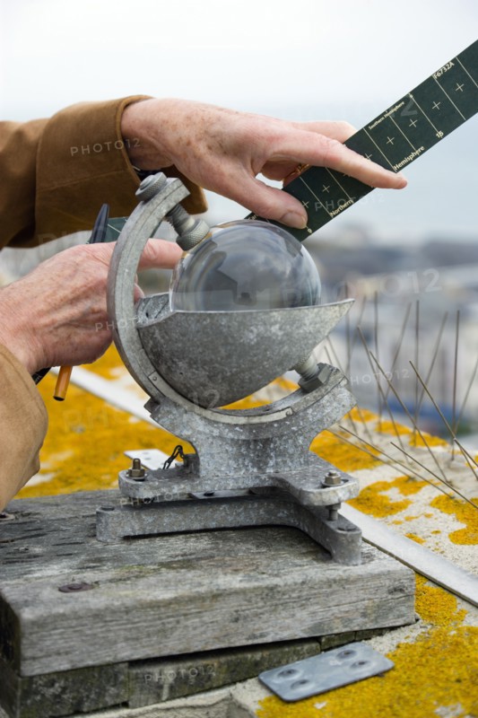 Climate, Weather, Measurements, CampbellStokes sunshine recorder or Stokes sphere on the top of the tallest building in Bognor Regis used by weather observers to monitor the hours of sunshine with observer inserting a summer card.