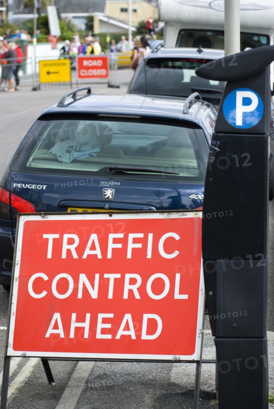 England, West Sussex, Bognor Regis, Solar panel powered Pay & Display parking meter on the sidewalk pavement for on street parking beside red Traffic Control Ahead sign with parked cars and a Road Closed and Diversion signs in the distance.