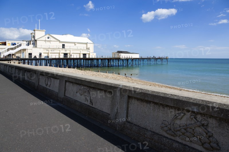 England, West Sussex, Bognor Regis, The Pier with people fishing off the end and the shingle pebble beach and the promenade with sea defence wall.
