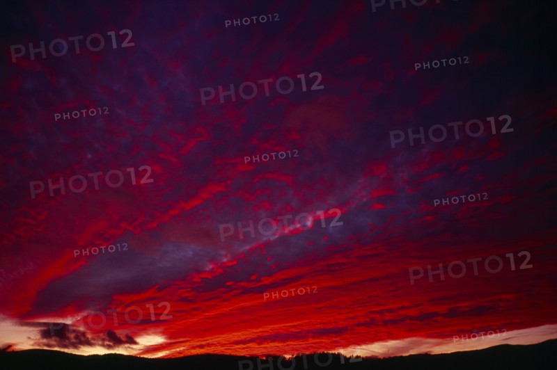 England, Climate, Sunset, Narrow  strip of land silhouetted against dramatic sunset sky with clouds lit red  pink  orange and purple.